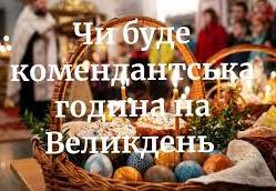 Зображення показує святкову великодню сцену. На передньому плані — кошик із великодніми стравами: пофарбовані яйця, паска, зелень та інші традиційні наїдки. Кошик стоїть на столі, поруч видно додаткові елементи святкового сервірування. На задньому плані — розмиті фігури людей у світлому приміщенні, що створює атмосферу святкування. Поверх зображення великим білим текстом українською мовою написано: «Чи буде комендантська година на Великдень».