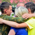 Фото на якому зображено як люди у цивільному одязі обіймають військового.