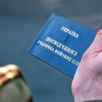 Рука тримає синє посвідчення учасника бойових дій від України