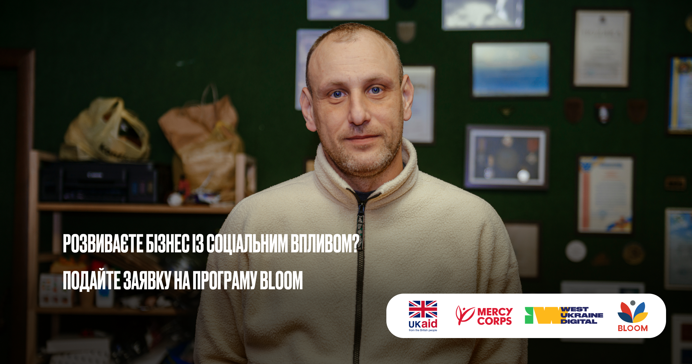Чоловік у флісовій куртці дивиться на камеру. Текст запрошує подати заявку на програму Bloom із логотипами UKaid, Mercy Corps