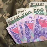 Купюри номіналом 200 та 500 гривень у кишені піксельного камуфляжу з прапором України
