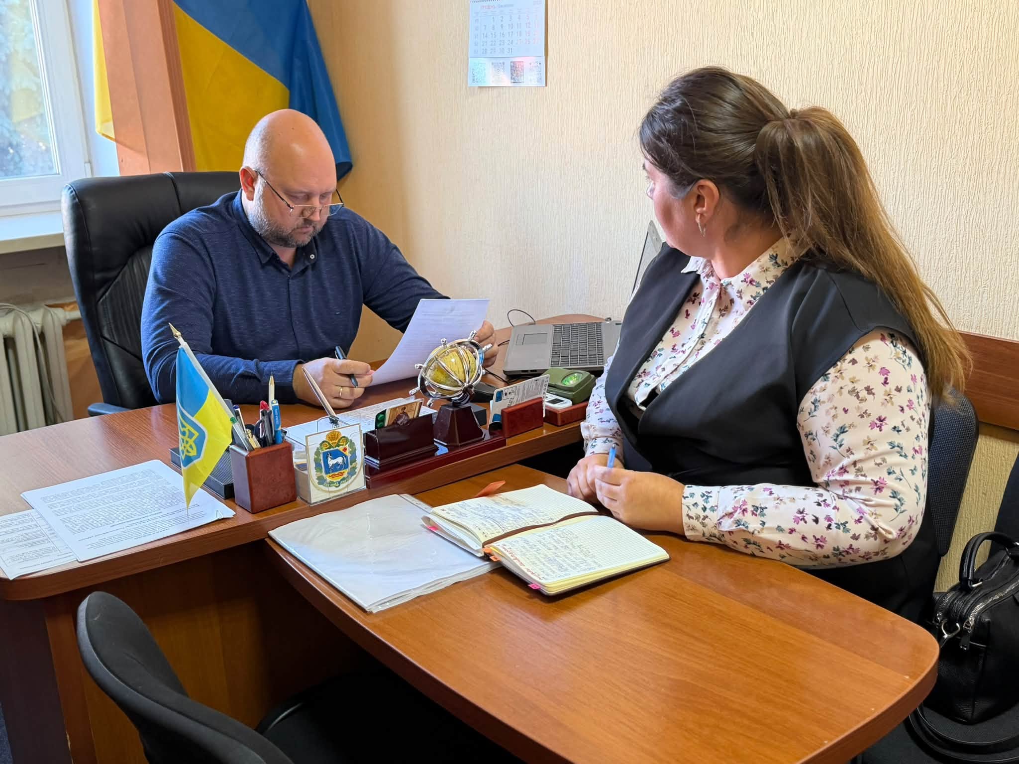 Чоловік за робочим столом спілкується з жінкою в кабінеті
