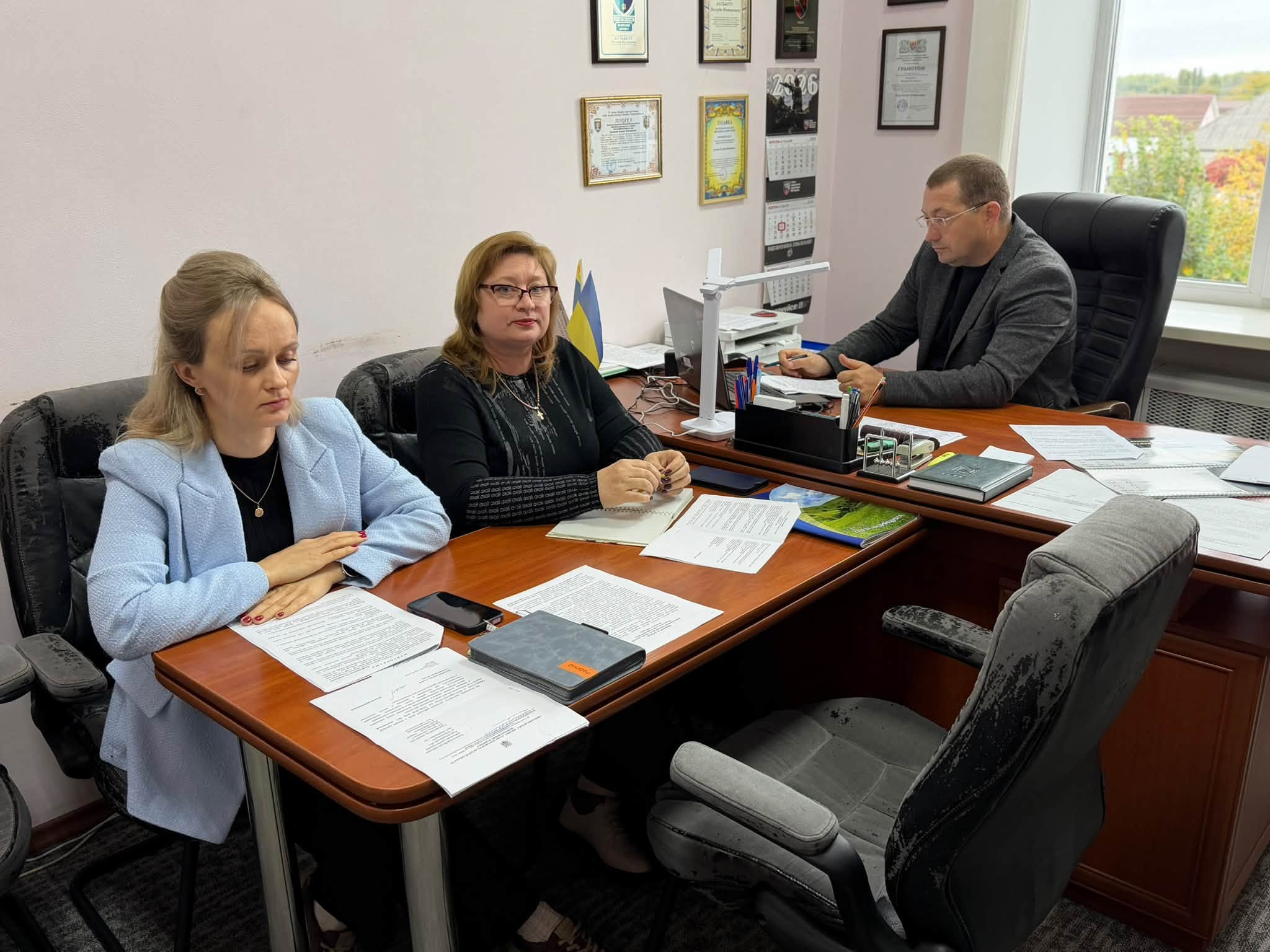 Троє людей сидять за довгим столом в офісі під час наради